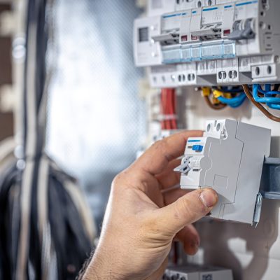 Male electrician at the checkout counter on a blurred background of a switchboard.